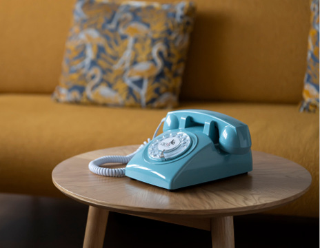 Téléphone rétro bleu à cadran rotatif sur une table en bois dans un décor d'hôtel
