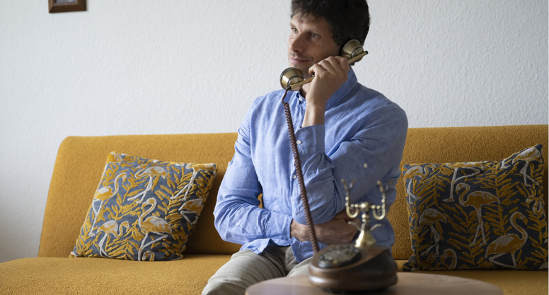 Homme sur un canapé utilisant un téléphone rétro orné