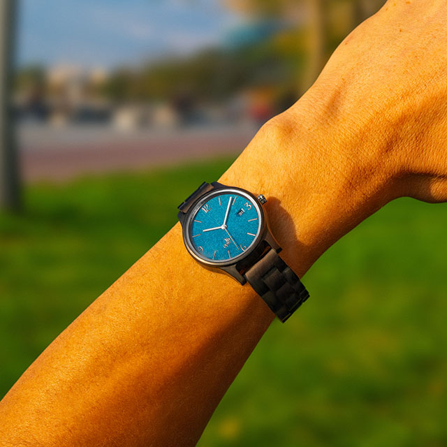 Opis UR-U1: Il classico orologio da polso unisex in legno, stile retrò - realizzato in sandalo nero con l’esclusivo quadrante goffrato in blu e parti metalliche in argento